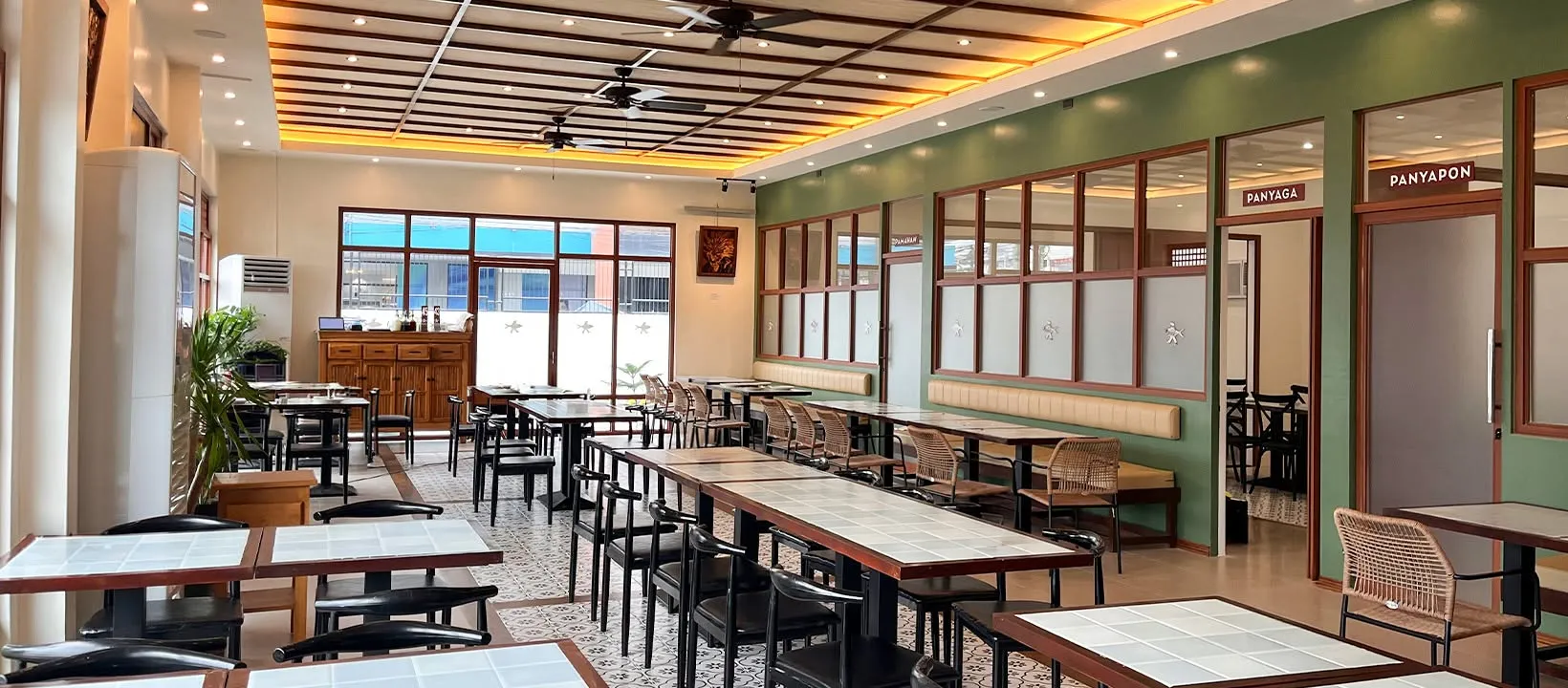 Parrilla's dining room: warm wood tables, ceiling fans, and a deep green feature wall